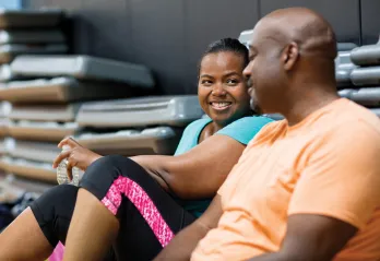 Man and woman sitting down and chatting in a group exercise room