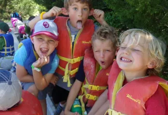 Four kids wearing life vests at a summer camp