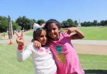 Two girls posting with a peace sign, with the arms around each other