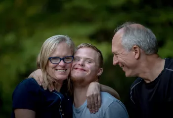 Women hugs son and man stands next to them