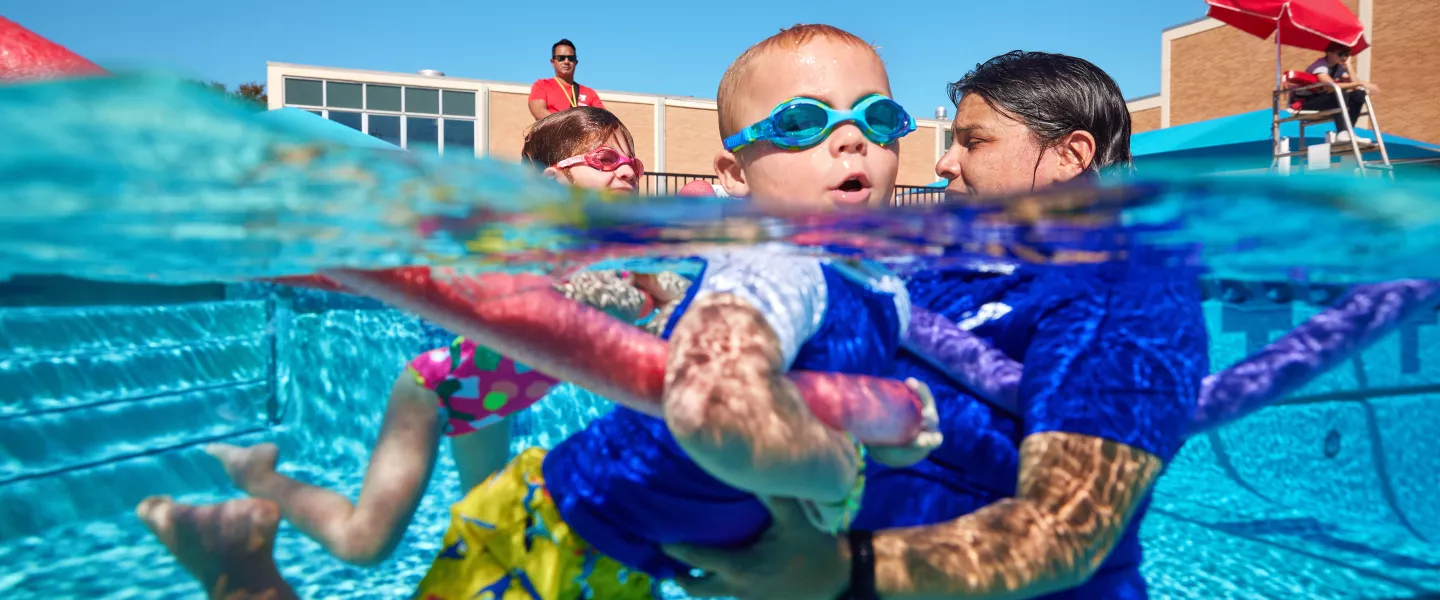 Swim instructor with kid and noodle for lessons