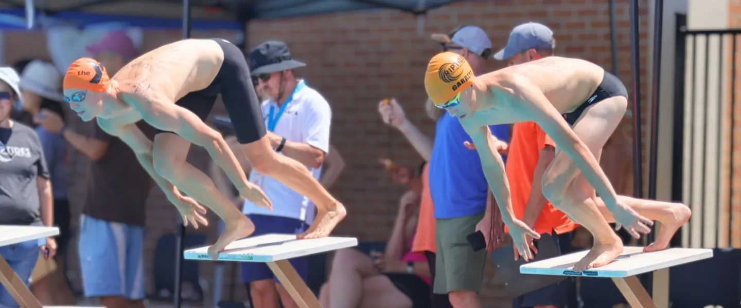 two swimmers on the starting block about to compete