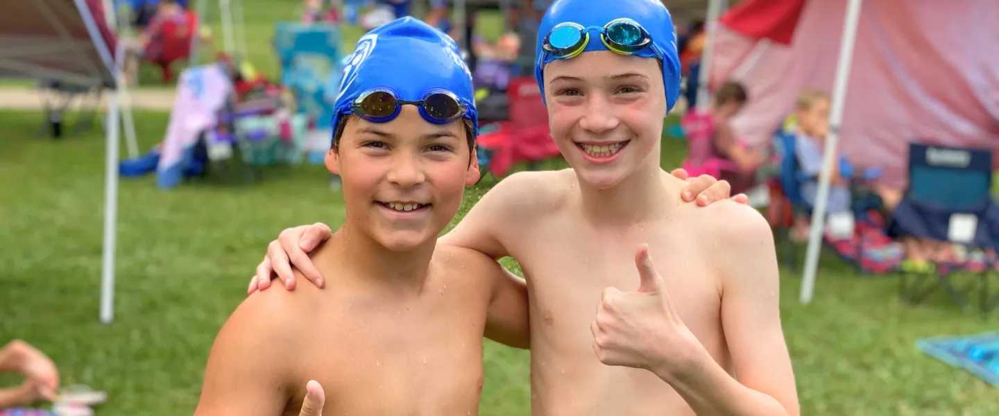 two boys smiling with thumbs up as part of swim team