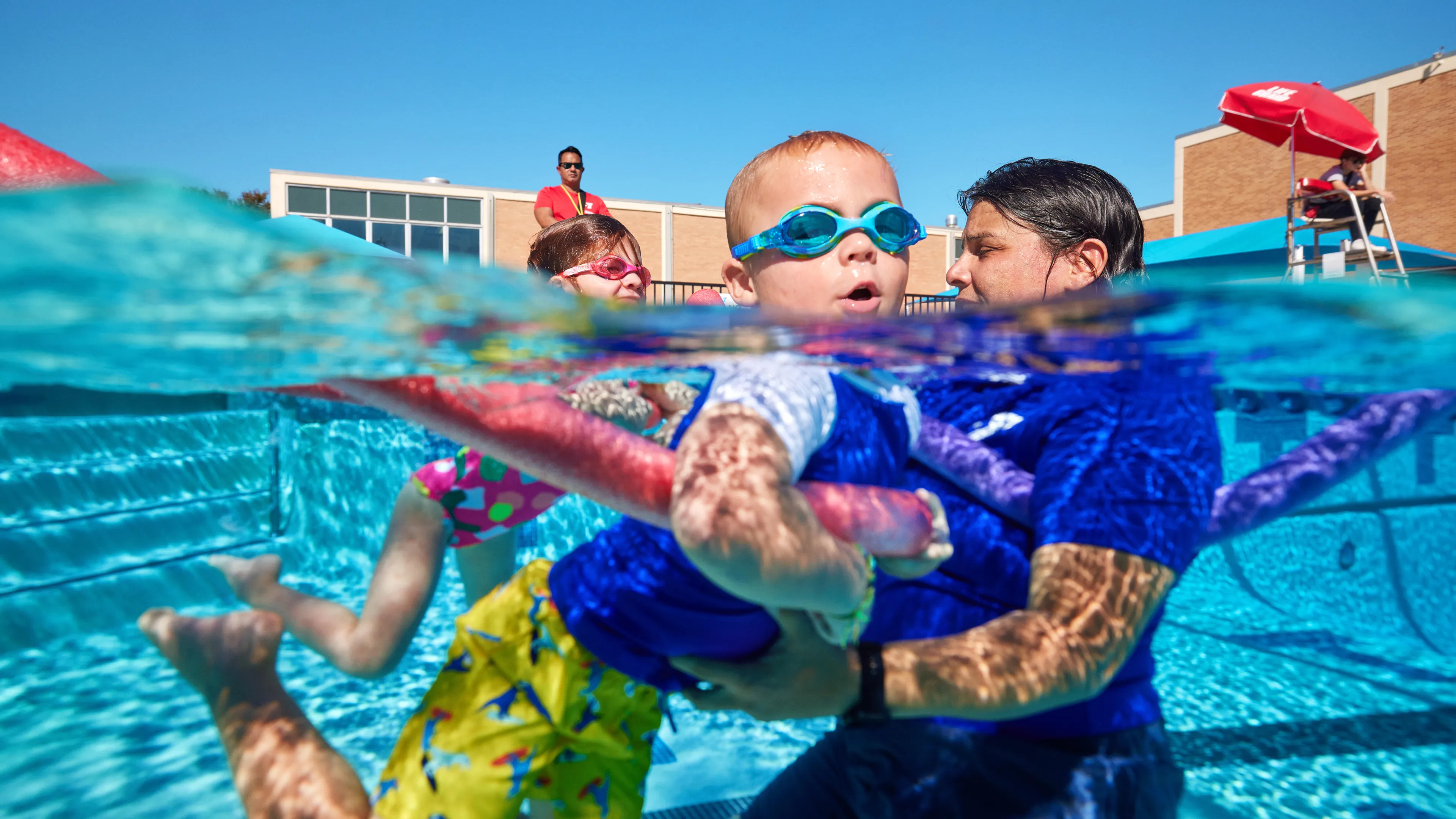 Swim instructor with kid and noodle for lessons