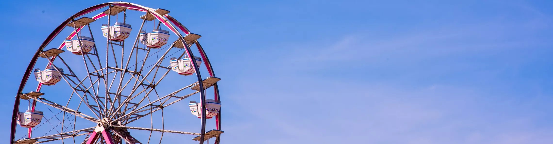 A ferris wheel shot from below with a blue sky behind