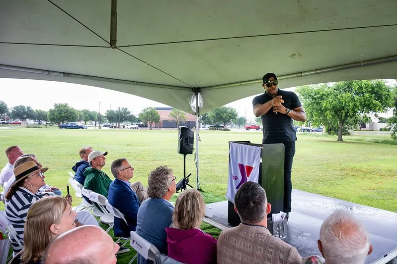 Desmond Mason speaking at the podium and pointing to his left