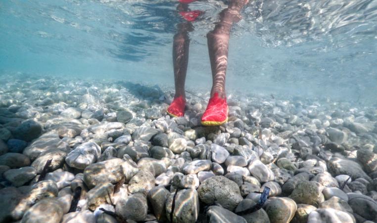 Young Adult Wearing Water Shoes for Walking at Rocky Shore stock photo
