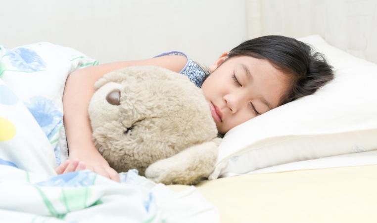 asian girl sleep and hug teddy bear on bed
