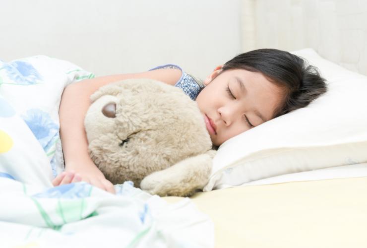 asian girl sleep and hug teddy bear on bed