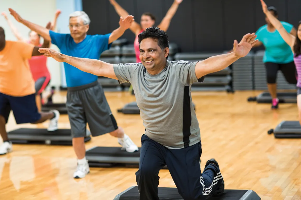 Man with his arms out in a stretched pose during a group exercise class