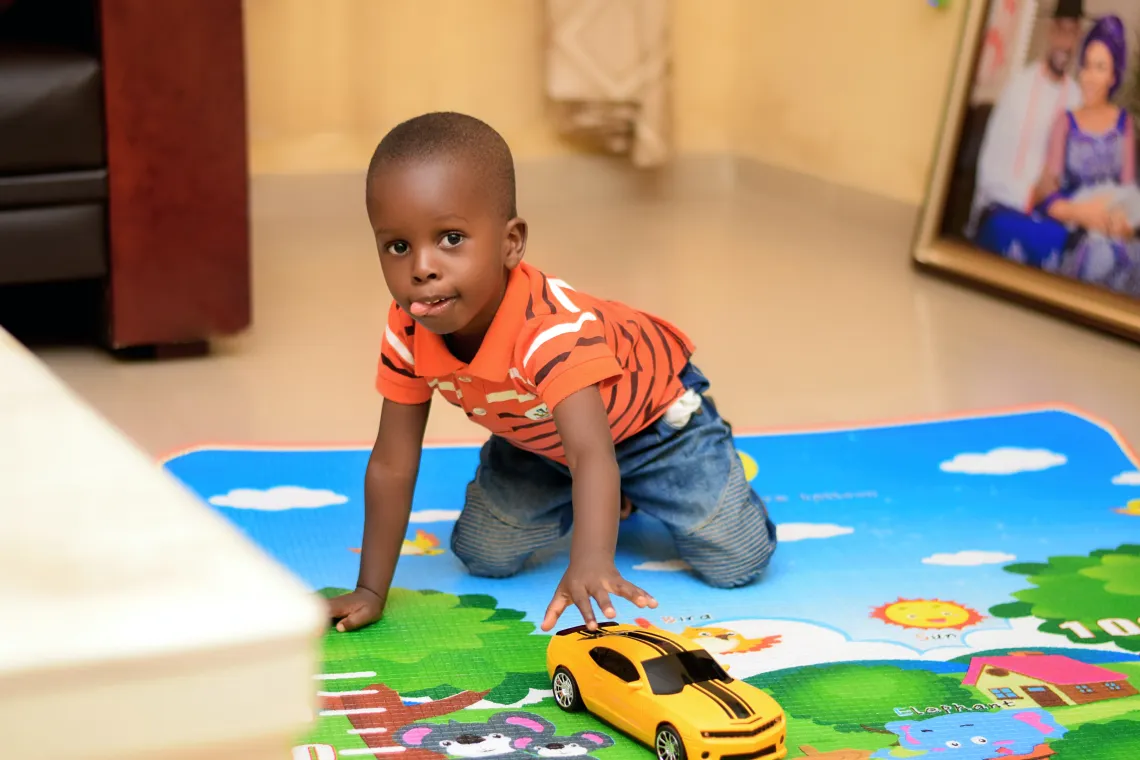 Child playing with a car on a play mat