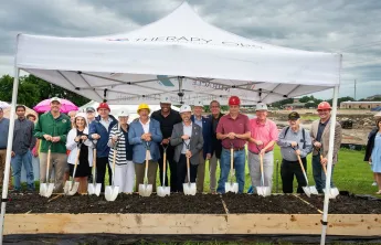 YMCA and local leadership posing with shovels in garden beds filled with dirt