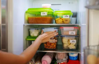Hand in refrigerator with containers 