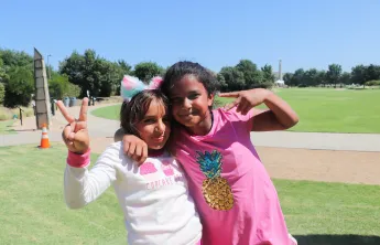 Two girls posting with a peace sign, with the arms around each other