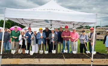 YMCA and local leadership posing with shovels in garden beds filled with dirt